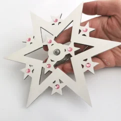 Drevená biela svietiaca hviezda na stromček s ružovými kamienkami.