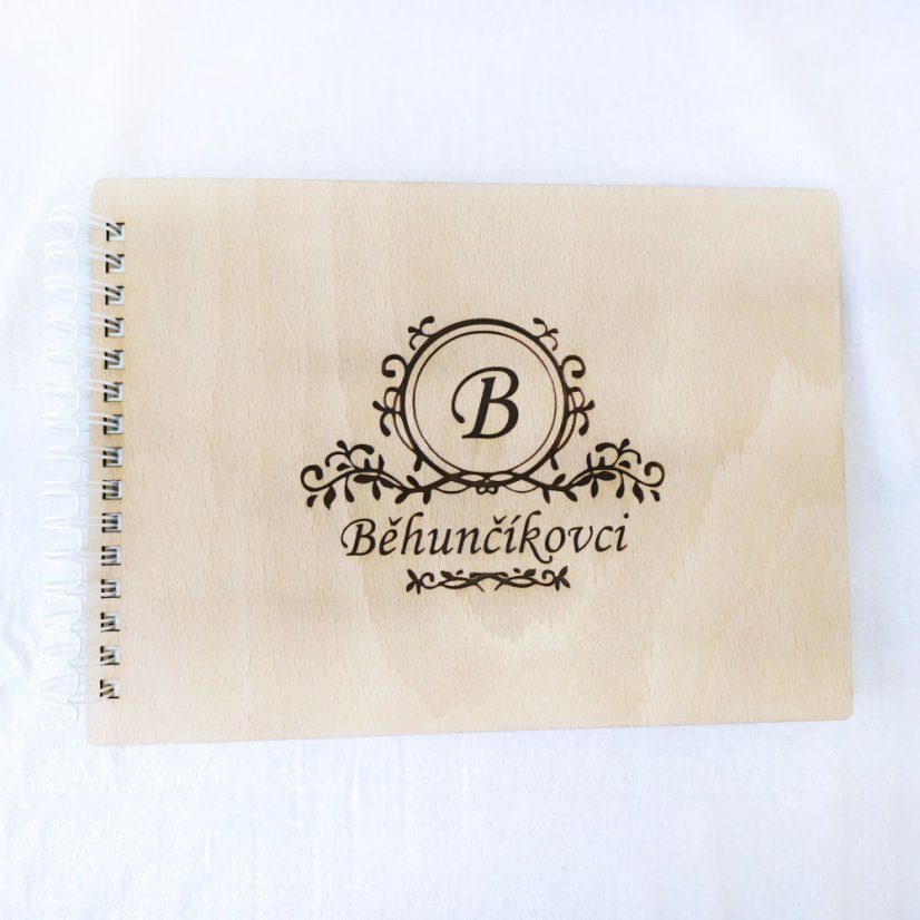 Drevený elegantný album s gravírovaným ornamentovým vzorom, v strede so začiatočným písmenom priezviska, pod ním gravírované priezvisko novomanželov.