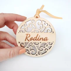 Detail drevenej vianočnej ozdoby s elegantným ornamentovým vzorom a s gravírovaným nápisom "Rodina".