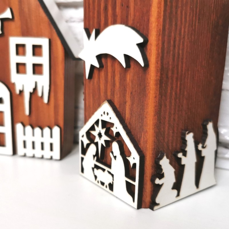 Detail dreveného hnedého svietnika zdobeného bielymi výrezmi na tému Betlehem.