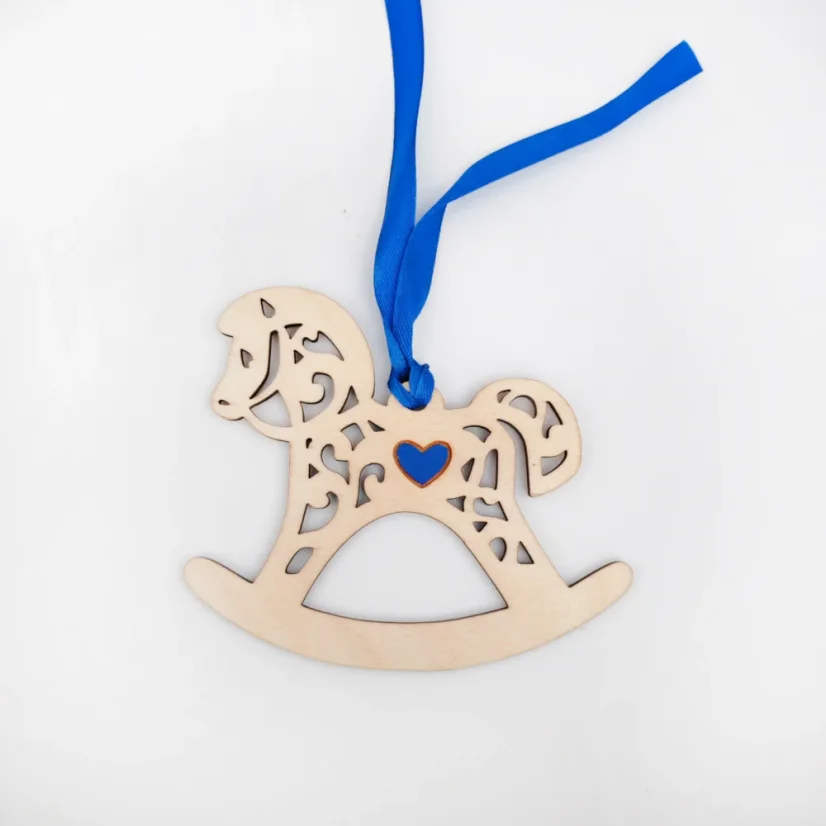 Drevená vianočná ozdoba v tvare húpacieho koníka s modrým srdiečkom v strede a stuhou v rovnakej farbe.