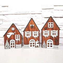 Tri drevené domčeky maľované hnedou lazúrou, zdobené bielymi výrezmi s vianočnými a zimnými motívmi.