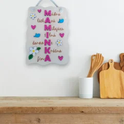 Drevená tabuľka Maminka s maľovanými detailmi zavesená v kuchyni.