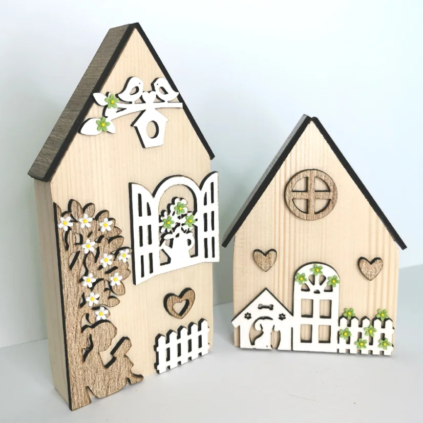 Masívne drevené domčeky zdobené výrezmi v rôznych farebných variáciách - okienka, kvety, strom, plot.