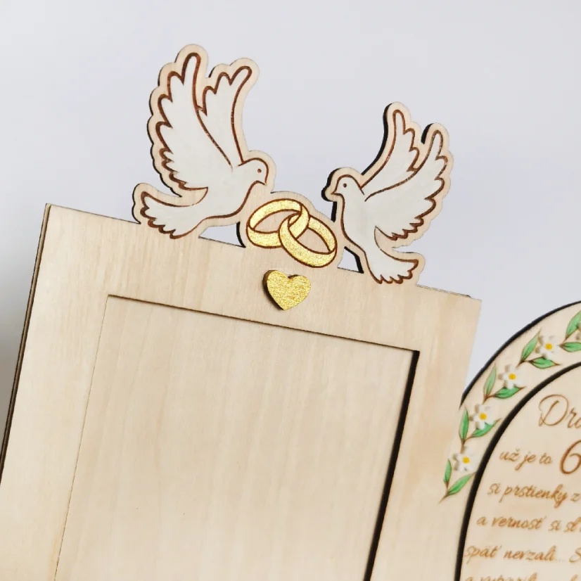 Detail rámiku s maľovanými holubicami so zlatými obrúčkami.