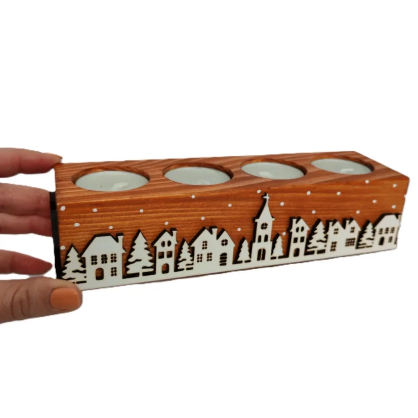 Drevený svietnik na štyri čajové sviečky v hnedom odtieni, zdobené výrezmi bielej zasneženej krajinky kolom dokola.