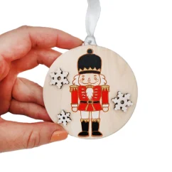 Drevená ozdoba s gravírovaným ručne maľovaným luskáčikom v červenej uniforme. Drevená ozdoba s gravírovaným ručne maľovaným luskáčikom v červenej uniforme.