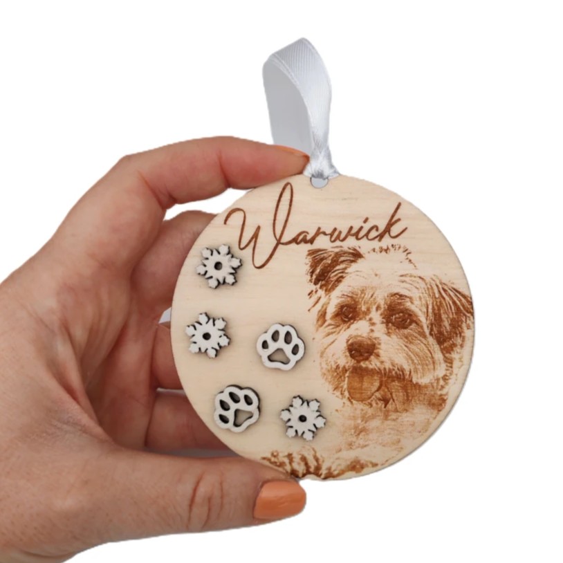 Drevená vianočná ozdoba s fotkou, menom, bielymi výrezmi vločiek a stuhou vo farbe podľa želania.