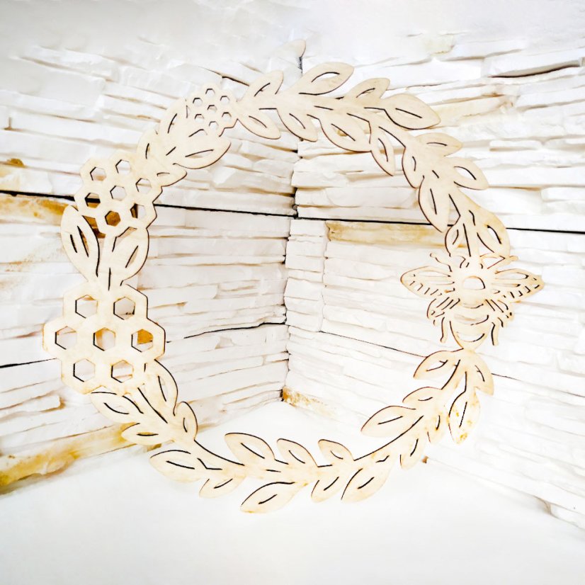 Drevený celoročný veniec na dvere s vyrezávanými motívmi listov, včelích plástov a včely.