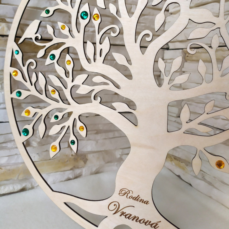 Detail dreveného stromu so smaragdovo zelenými a zlato žltými kamienkami.