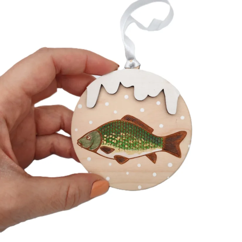 Drevená ozdoba na stromček s maľovaným vianočným kaprom, s bielou stuhou.