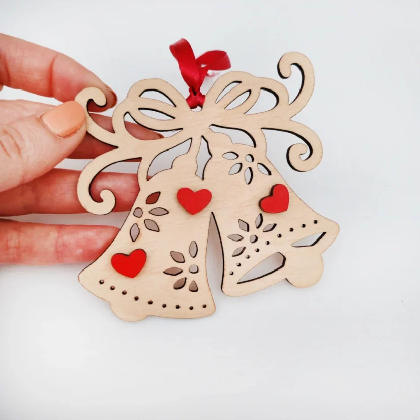 Drevená vianočná ozdoba v tvare zvončeka s červenými srdiečkami a stuhou.