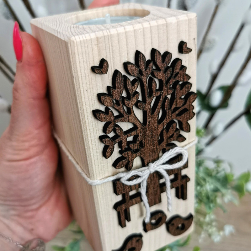 Detail dreveného svietnika zo smreku s hnedým výrezom stromu, lavičky a vtáčikov.