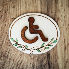 Drevená tabuľka s hnedým symobolom pre označenie ZŤP s gravírovanými ručne maľovanými jemnými lístkami.