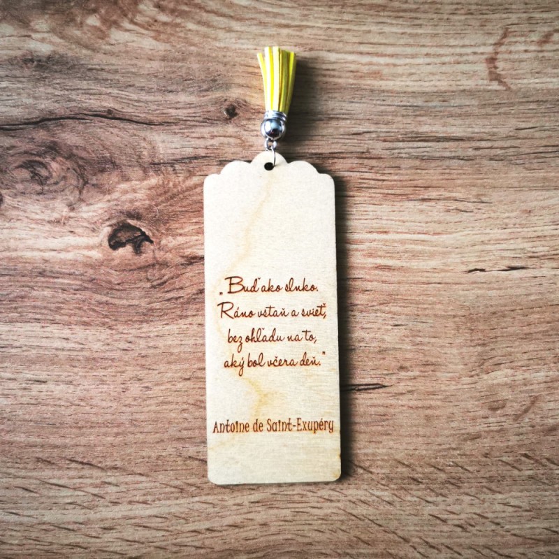 Druhá strana drevenej záložky s gravírovaným citátom: "Buď ako slnko. Ráno vstaň a svieť, bez ohľadu na to, aký bol včera deň." Antoine de Saint-Exupéry