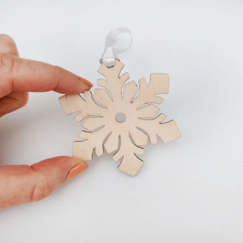 Drevená vianočná ozdoba snehová vločka so stuhou.