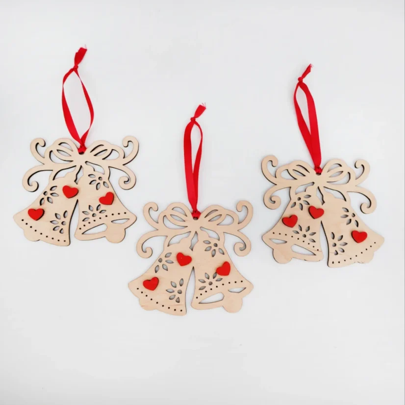 Drevené vianočné ozdoby v tvare zvončekov s červenými srdiečkami a stuhou.