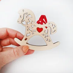 Drevená vianočná ozdoba v tvare húpacieho koníka s červeným srdiečkom v strede a stuhou v rovnakej farbe. Drevená vianočná ozdoba v tvare húpacieho koníka s červeným srdiečkom v strede a stuhou v rovnakej farbe.