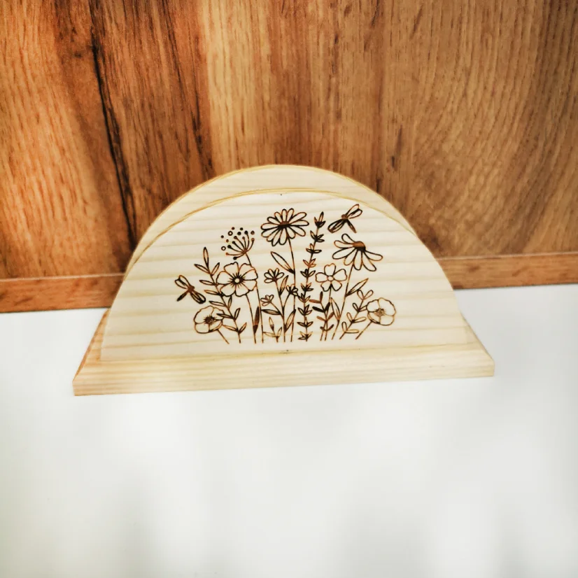 Drevený stojan na servítky s gravírovanými lúčnymi kvetmi.
