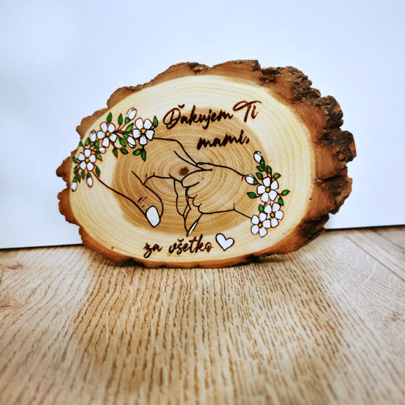 Stojaci agátový krúžok s gravírovaným textom "Ďakujem Ti mami za všetko" s maľovanými bielymi kvetmi okolo dvoch držiacich sa rúk.