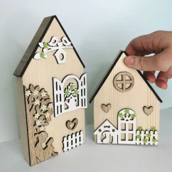 Masívne drevené domčeky zdobené výrezmi v rôznych farebných variáciách - okienka, kvety, strom, plot.