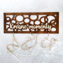 Drevená dekorácia na zavesenie fotiek s nápisom "Krásne momenty" na stenu.