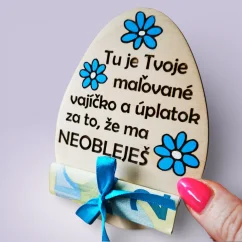 Drevené vajíčko s modrými maľovanými kvietkami a textom "Tu je Tvoje maľované vajíčko a úplatok za to, že ma neobleješ."