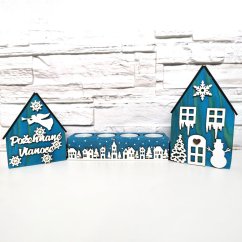 Drevené domčeky v modrej lazúre a k nim zladený svietnik, ktorý je zdobený bielou zasneženou krajinkou kolom dokola.