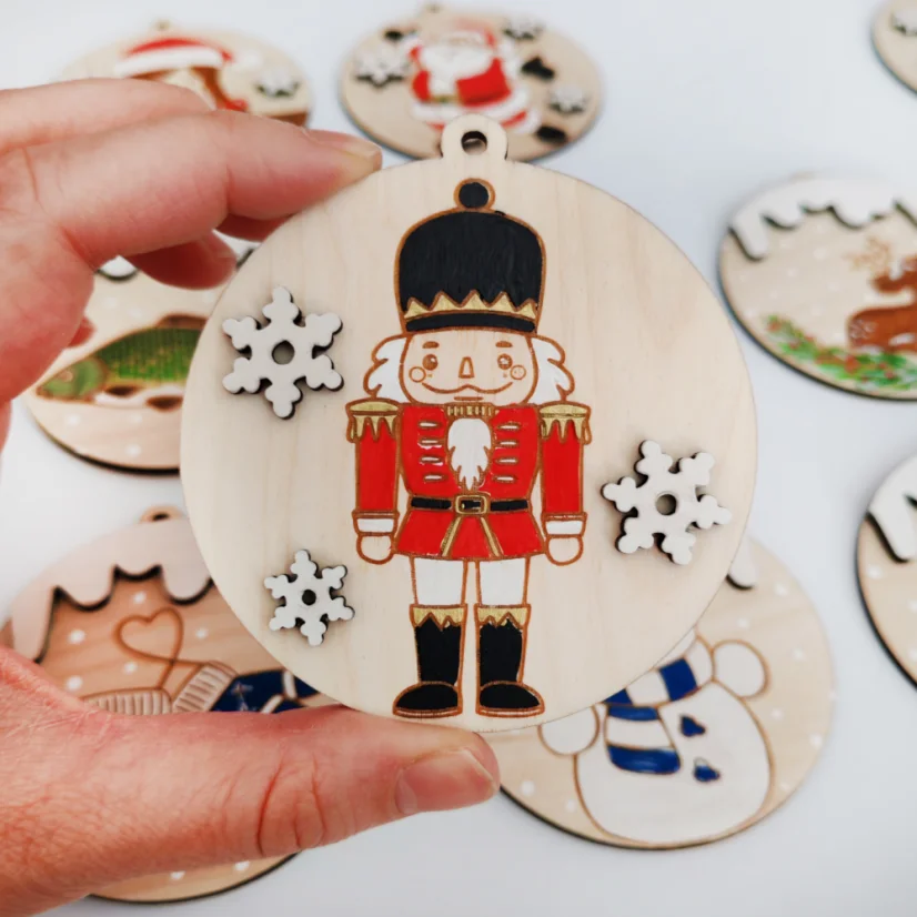 Drevená ozdoba s gravírovaným ručne maľovaným luskáčikom v červenej uniforme.