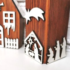 Detail dreveného hnedého svietnika zdobeného bielymi výrezmi na tému Betlehem.