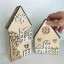 Masívne drevené domčeky zdobené výrezmi v rôznych farebných variáciách - okienka, kvety, strom, plot.